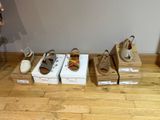several pairs of shoes are lined up on boxes on a wooden floor