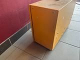 a yellow box sitting on a tiled floor next to a red wall