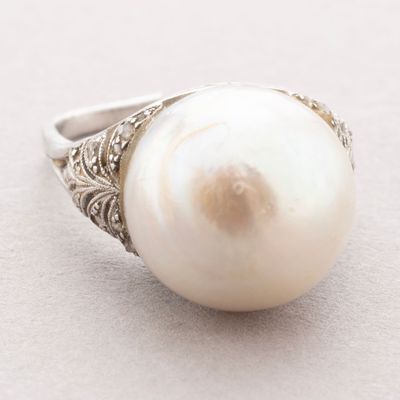 une photo d'une bague en perle blanche posée sur une surface blanche