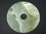 green jade disc with a hole in the middle on a black surface