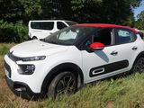 une petite voiture blanche garée dans un champ, à côté d'une camionnette