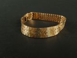 bracelet made of gold - plated metal on a black surface