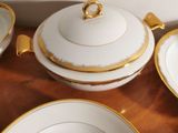 several white and gold plates and bowls on a wooden table