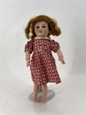 une image représentant une poupée aux cheveux roux et vêtue d'une robe rouge