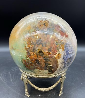 une image représentant une boule en verre posée sur un socle doré