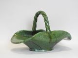a green basket with a handle on a white surface