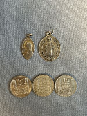 trois pièces d'or et une médaille d'argent posées sur un socle en argent
