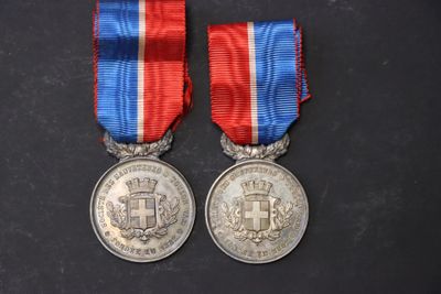deux médailles en argent avec des rubans rouge, blanc et bleu sur une surface noire