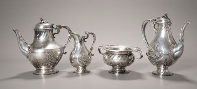 trois théières en argent et deux tasses en argent posées sur une table