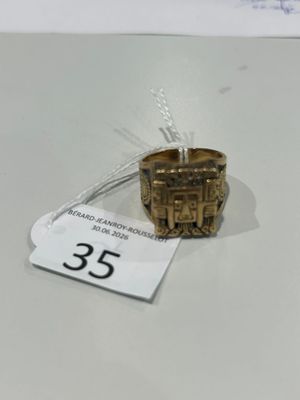 une bague en or ornée d'un château, posée sur une table