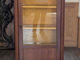 une petite armoire avec une porte vitrée au milieu d'une pièce