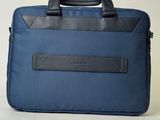 blue laptop bag with black leather handles on a white surface