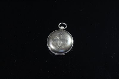 une petite montre de poche en argent posée sur une surface noire