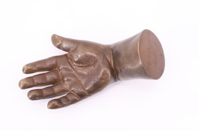 une statue en bronze représentant une main tenant une coupe