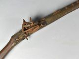 un vieux pistolet avec une poignée en bois sur une surface blanche