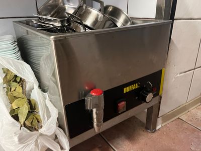 Des casseroles et des poêles sont empilées sur une cuisinière dans une cuisine.