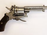 un vieux revolver avec une poignée en bois sur une surface blanche