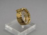 une photo en gros plan d'une bague en or posée sur un socle transparent