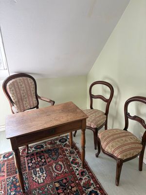 plusieurs chaises et une table dans une pièce dont le sol est recouvert d'un tapis