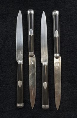 four knives are lined up on a black surface