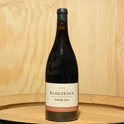 a bottle of wine sitting on top of a wooden barrel
