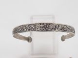 a close up of a silver bracelet with flowers on it