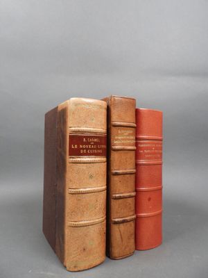 three old books sitting on top of each other on a gray surface