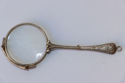 une loupe munie d'un manche, posée sur une table