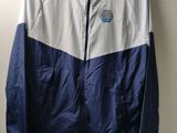 une veste blanche et bleue accrochée au mur à côté d'un cintre en bois
