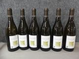 six bouteilles de vin blanc sont alignées sur une table