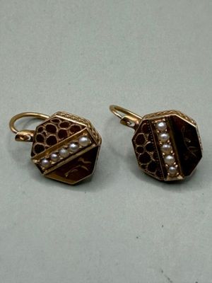 pair of gold tone earrings with pearls on them sitting on a table