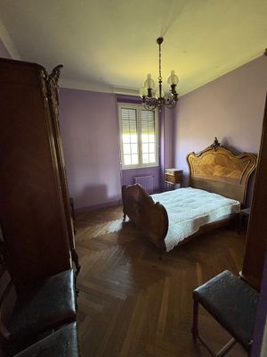 une chambre à coucher avec un lit, une chaise et un lustre