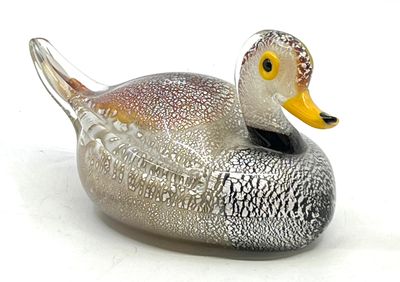 un canard en verre posé sur une surface blanche