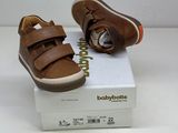 brown leather baby shoes with velcro straps on top of a white box