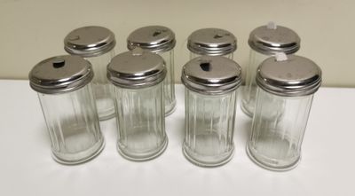 six glass salt and pepper shakers lined up on a table