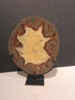 une assiette marron ornée d'une feuille, posée sur un socle