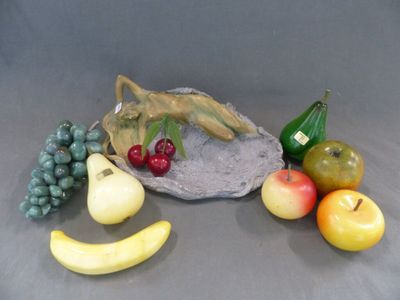 une figurine représentant un lézard assis sur un rocher, entouré de fruits et de légumes