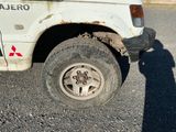 un camion blanc avec un pneu crevé, garé sur le bord de la route