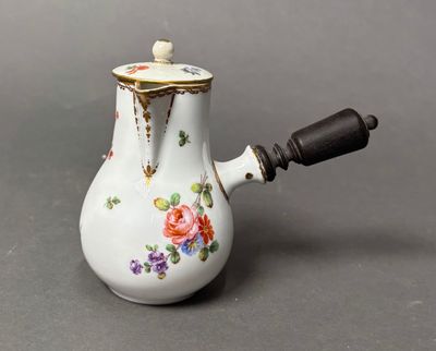 a small white tea pot with flowers on it
