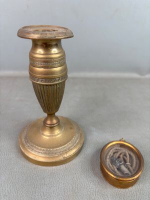 un petit vase en or posé à côté d'une pièce de monnaie sur une table