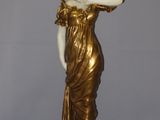 statue of a woman in a gold dress with her hand on her hip
