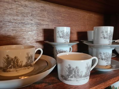 Plusieurs tasses et soucoupes sont posées sur une étagère dans une pièce