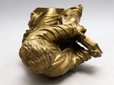 a gold figurine of a man laying on his back