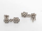 une paire de boucles d'oreilles en argent posées sur une surface blanche