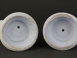 two white vases sitting on top of a table next to each other
