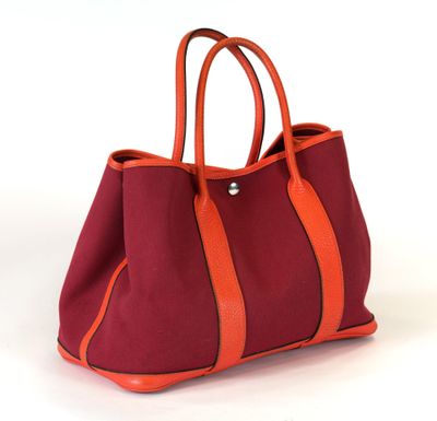 un sac à main orange et rouge posé sur une surface blanche