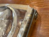 a silver clock sitting on a wooden table with a glass cover
