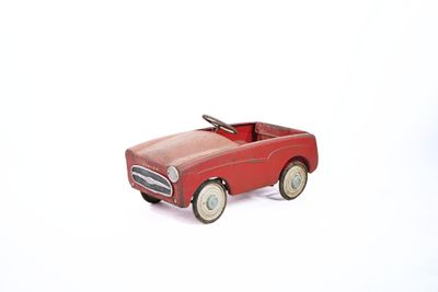 a red toy car that is sitting on a white surface