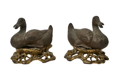 une paire de canards en fonte posés sur des souches d'arbre, sur fond blanc