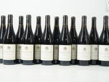 six bouteilles de vin sont alignées sur une surface blanche